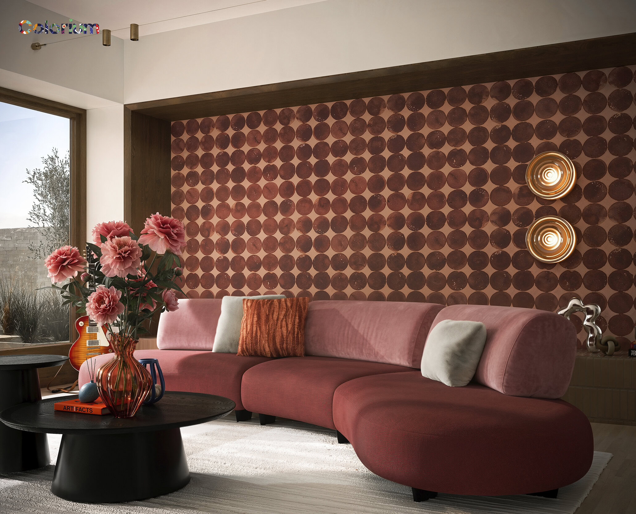 Elegant pink sofa with plush cushions in a contemporary living room setting, featuring a textured wall with circular patterns and stylish lighting fixtures.