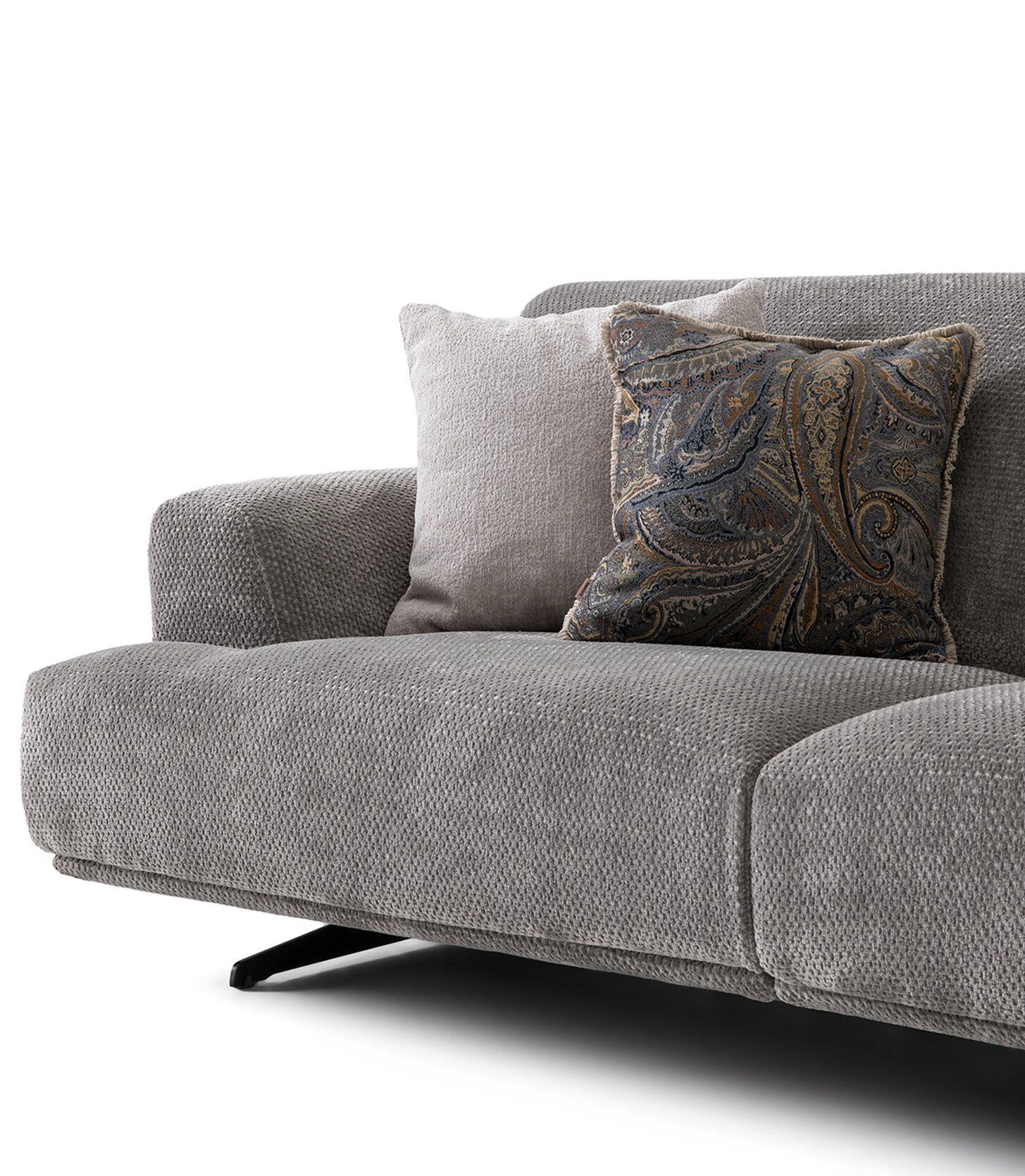 O canapea modernă din material textil gri, cu două perne decorative, una simplă gri deschis și una cu un model paisley complex, perfectă pentru decorul contemporan al camerei de zi.