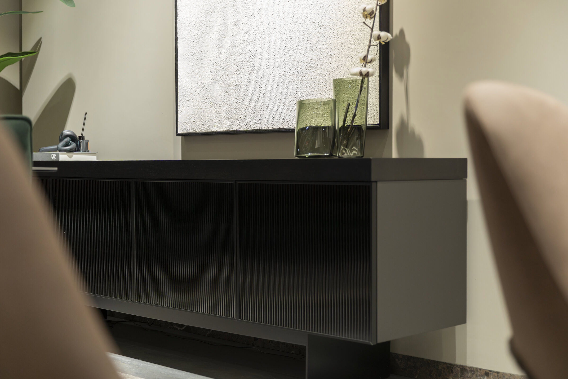 Bufet contemporan negru cu uși glisante cu nervuri, decorat cu vaze din sticlă verde și un aranjament floral minimalist, ideal pentru mobilier modern de living sau sufragerie.