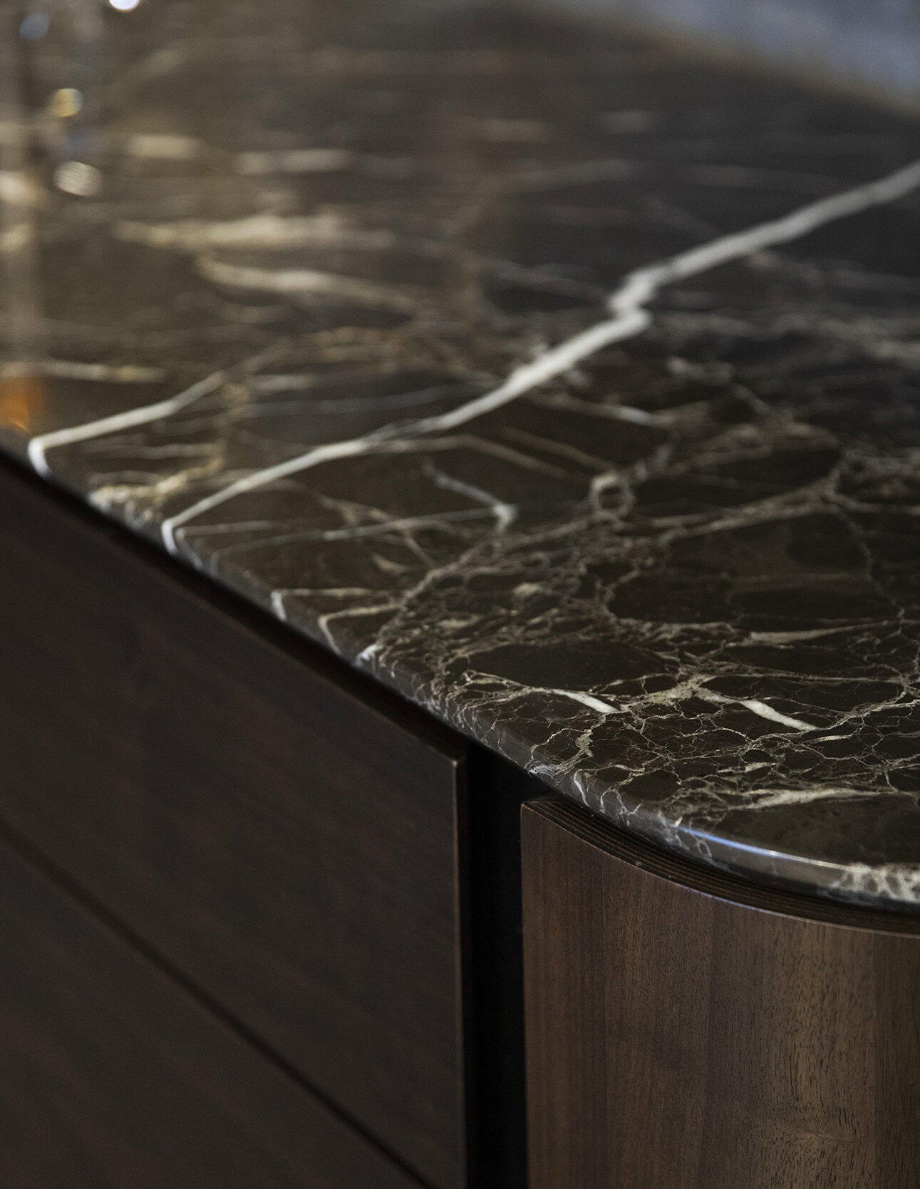 Luxurious dark marble countertop with white veining on wooden cabinetry for elegant home decor.