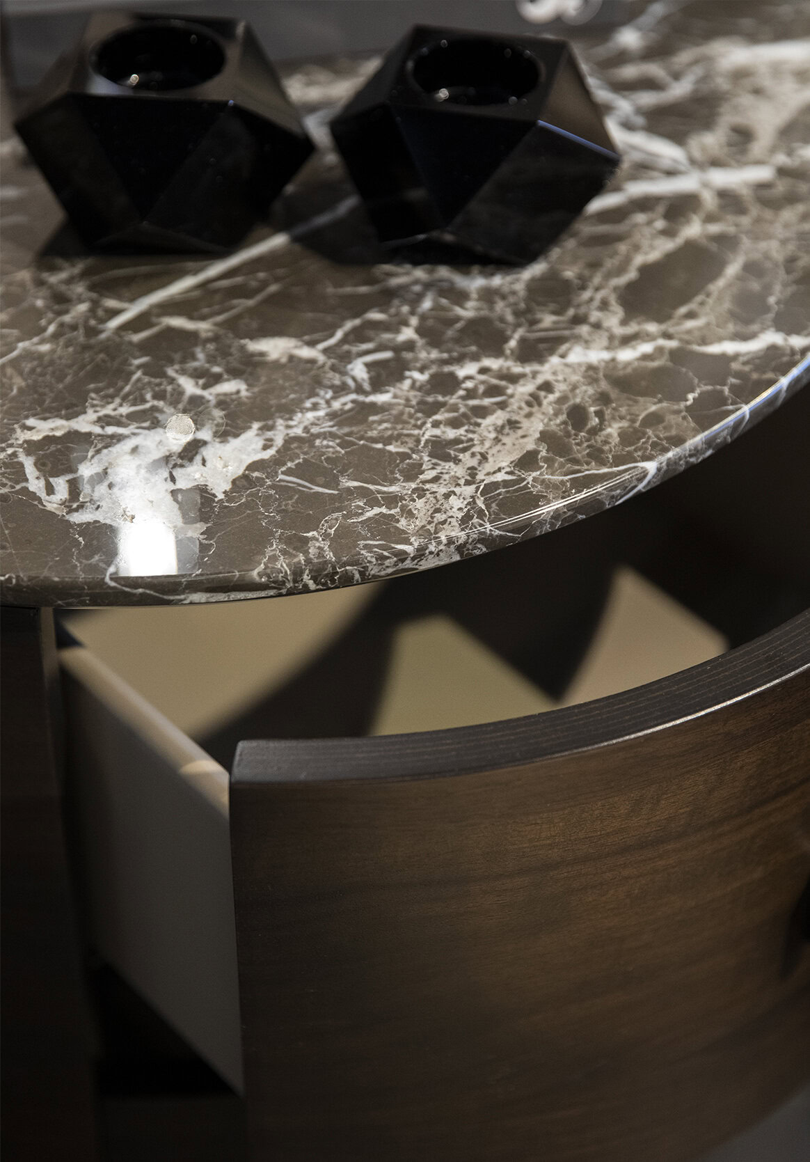 Luxurious dark marble tabletop with white veining, paired with elegant dark wood furniture and modern black geometric decor pieces, creating a sophisticated and stylish living space.