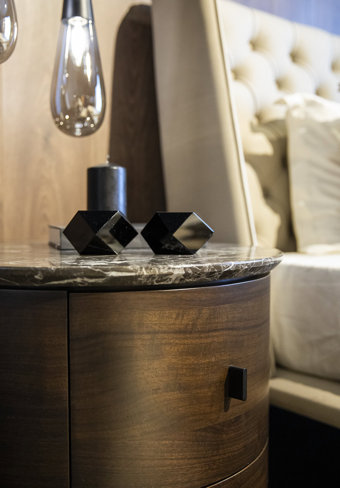 Elegant wooden nightstand with marble top, modern black decorative objects, and ambient side lighting for bedroom decor.