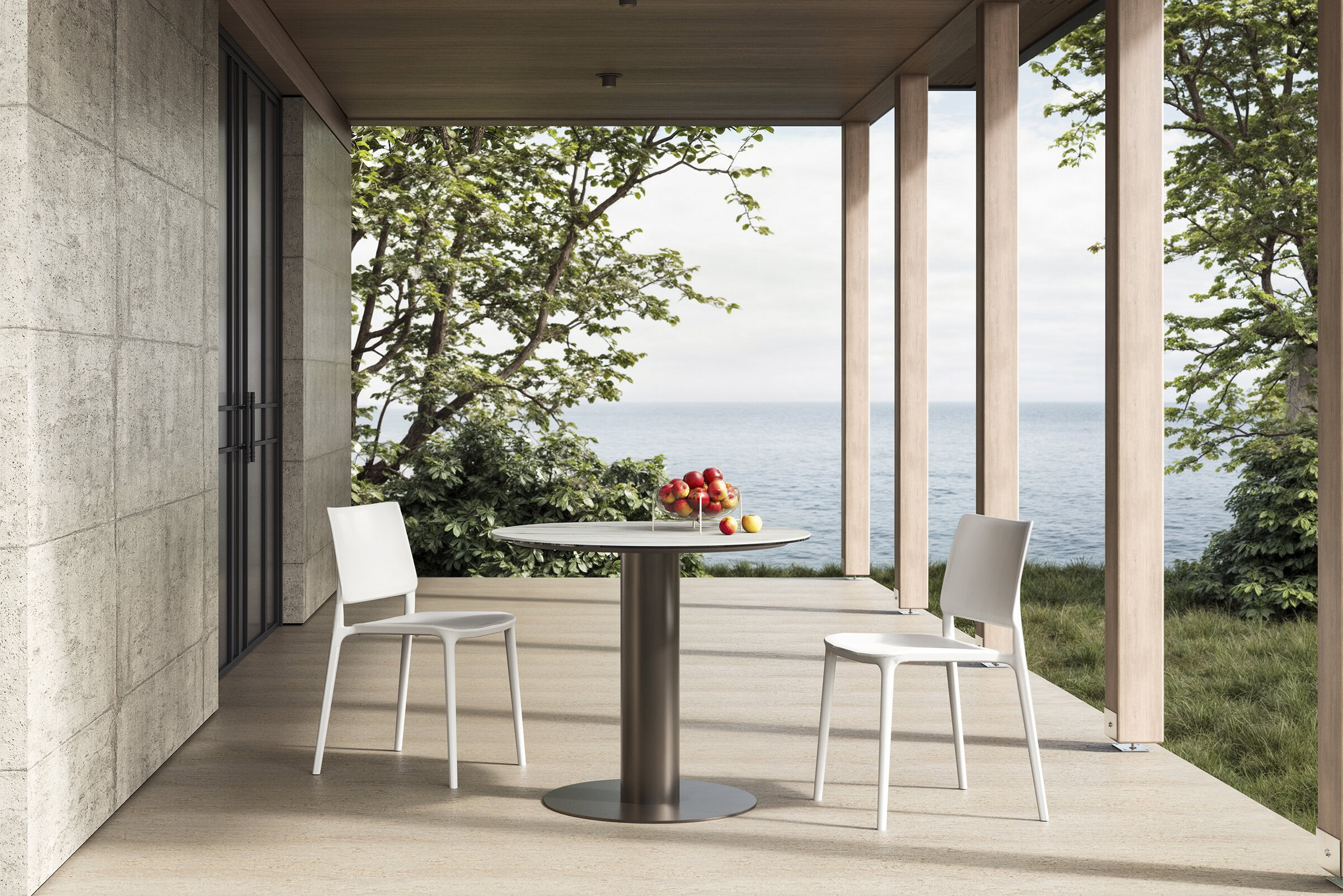 Scaune de sufragerie moderne, albe și elegante, și o masă rotundă pe un balcon cu vedere la ocean, cu verdeață, prezentând un design contemporan de mobilier pentru spații exterioare și viața de coastă.