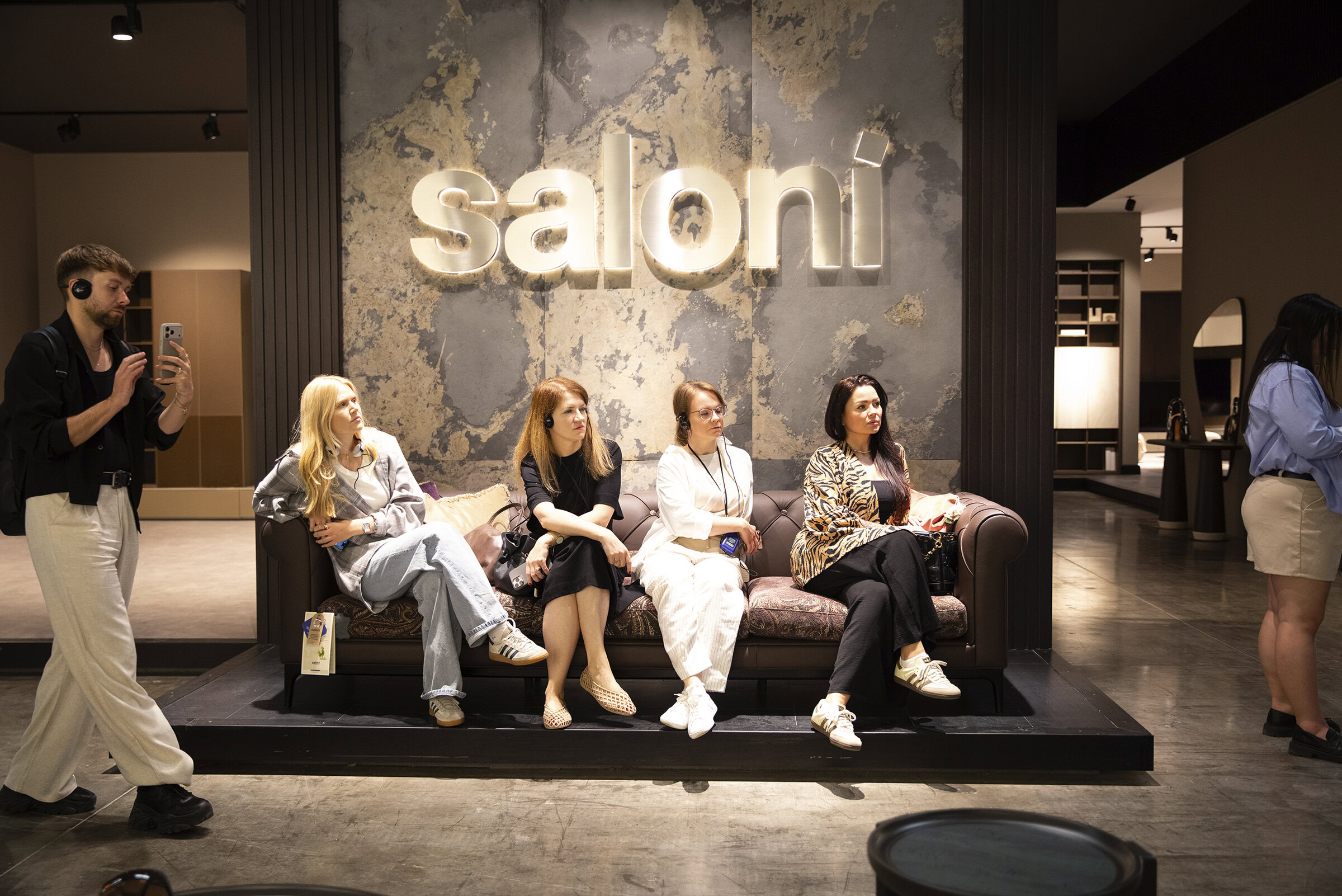 Modern Saloni Furniture showroom featuring a stylish seating area with five women and a man, showcasing contemporary furniture and interior design at Saloni Furniture.