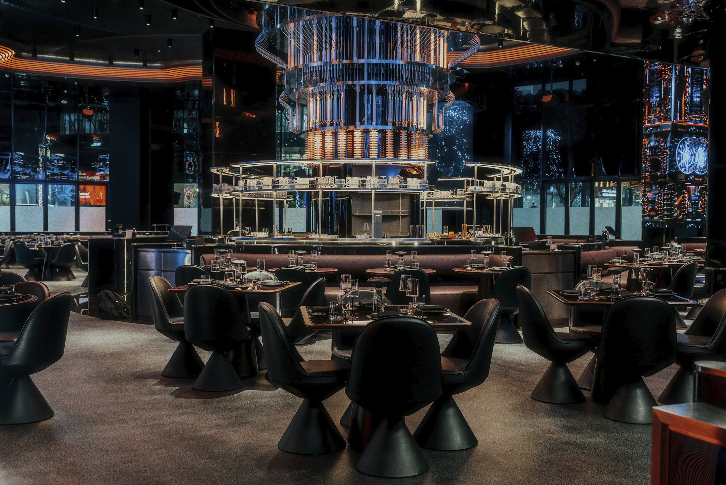 Luxury modern restaurant interior with sleek black chairs, elegant table settings, and eye-catching ambient lighting in a high-end dining establishment.
